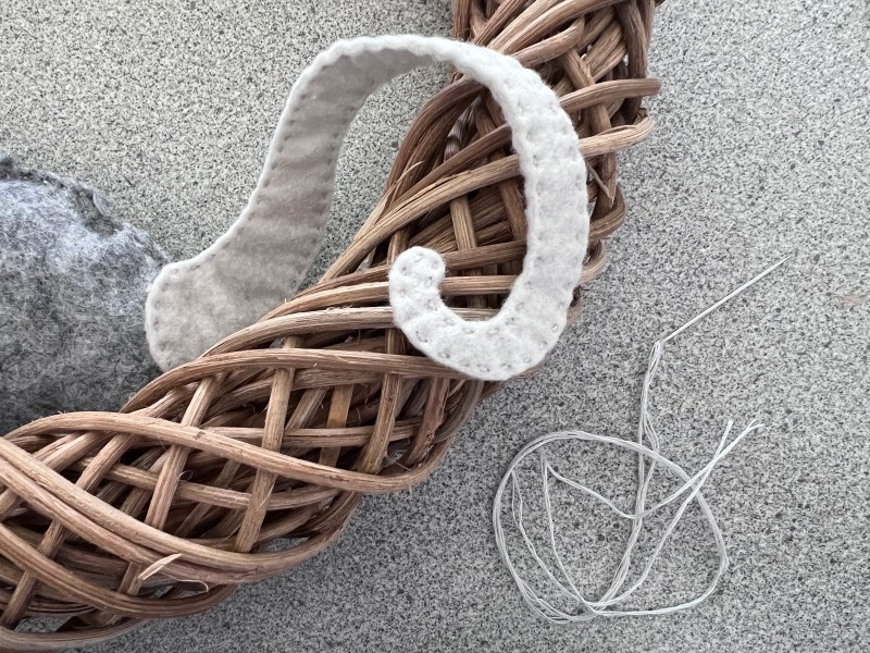 A tail made of felt draped around a wreath made of vines.